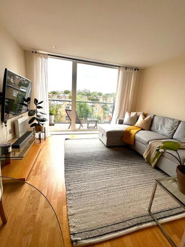 a living room with a couch and a large window at Flat in Arsenal Islington Central London in London