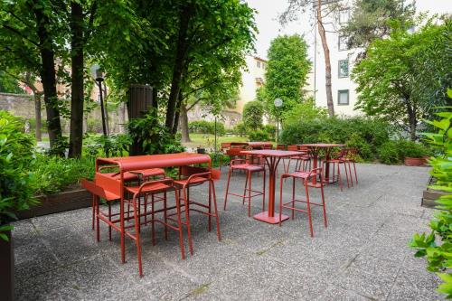a group of red tables and chairs in a park at Mercure Bologna Centro in Bologna