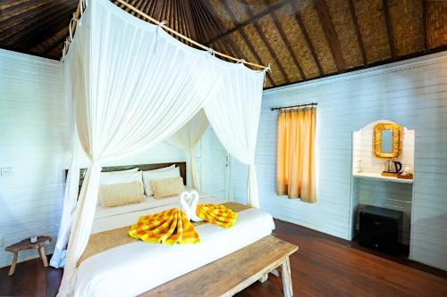 a bedroom with a white bed with a canopy at Wellhouse Villas in Nusa Lembongan