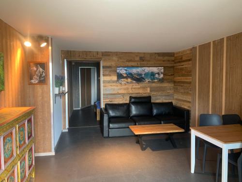 a living room with a black leather couch and a table at Appartment Emosson 2 in Finhaut