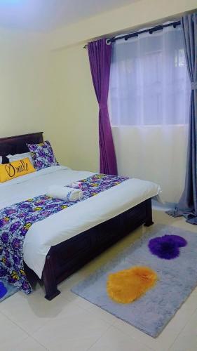 a bedroom with a bed with a window and a rug at Nadelle Cozy Homes in Bonyunyu