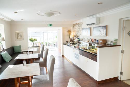 a restaurant with tables and chairs and a kitchen at ChiemseeStern Vacation & Recreation "Adults Only" in Gstadt am Chiemsee