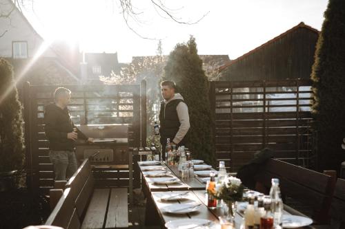 two men standing on a patio with a table at XXL-Ferienwohnung Blumenwiese in Hayingen