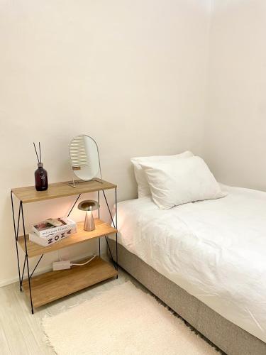 1 dormitorio con cama y mesita de noche con espejo en Letters Share House, en Wonju