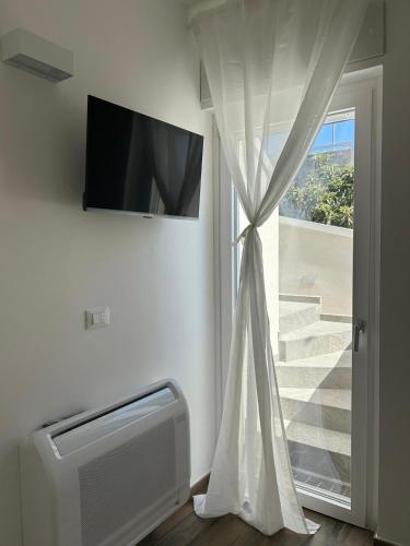 a window with a curtain and a television on a wall at Le Dimore di Fefè in Alberobello
