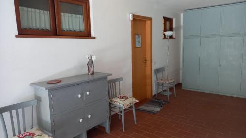 a room with a dresser and two chairs and a door at L'Ulivo, alloggio in seminterrato in Fornello