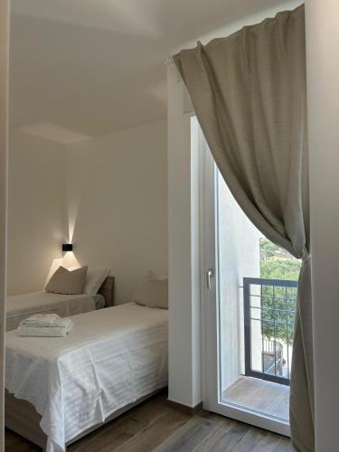 a white bedroom with a bed and a window at Le Dimore di Fefè in Alberobello
