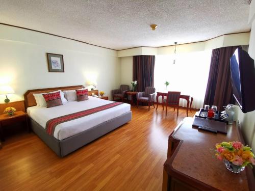 a hotel room with a large bed and a desk at Duangtawan Hotel Chiang Mai in Chiang Mai