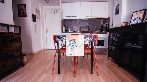 a kitchen with a table with orange chairs and white cabinets at Apartaments Muntaner I in Palamós