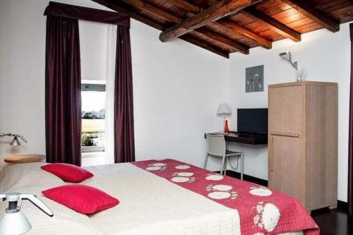 a bedroom with a bed with red pillows and a desk at Relais Villa D'Assio in Labro Rieti