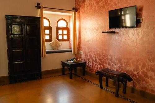 a room with a tv on the wall and a table at Jaisalmer Elite Castle in Jaisalmer