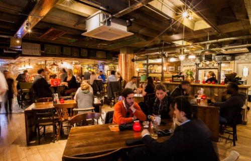 a group of people sitting at tables in a restaurant at Virexxa Bedford Centre - Alpha Suite - 2Bed Flat with Free Parking & Gym in Bedford