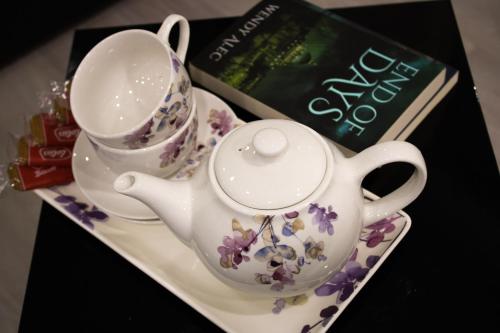 a tea set on a plate next to a book at Virexxa Bedford Centre - Alpha Suite - 2Bed Flat with Free Parking & Gym in Bedford