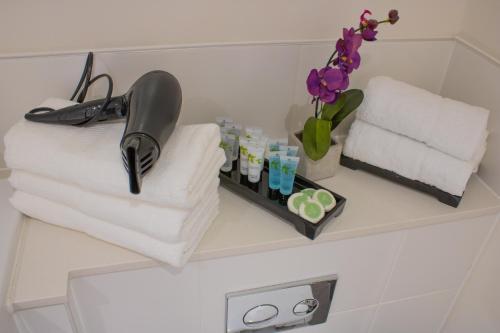 a shelf in a bathroom with towels and flowers at Virexxa Bedford Centre - Alpha Suite - 2Bed Flat with Free Parking & Gym in Bedford