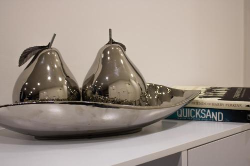 two pears in a bowl on a table with books at Virexxa Bedford Centre - Alpha Suite - 2Bed Flat with Free Parking & Gym in Bedford