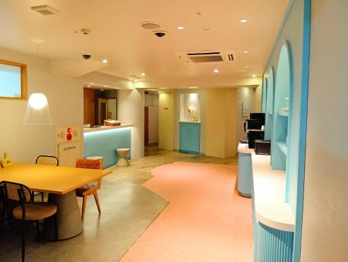 a living room with a table and a kitchen at Nesthotel alt Kawasaki Station in Kawasaki