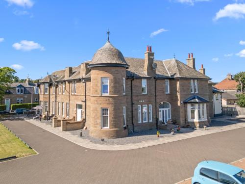 a large brick building with a roof on a street at Panmure Apartment in Monifieth