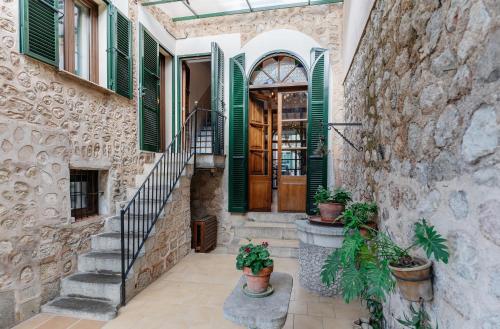 a stone house with green shutters and stairs at Hotel Casa Bougainvillea in Sóller