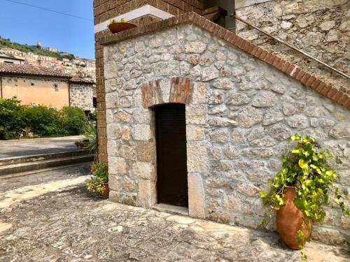 a stone building with a door and a plant at La Caveja in Pietravairano