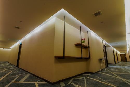 a hallway with a wall with a shelf and a vase of flowers at NB HOTEL in Johor Bahru