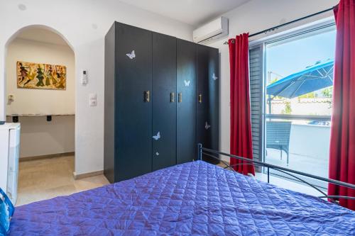 a bedroom with a blue bed and a large window at Relaxrooms in Lefkímmi