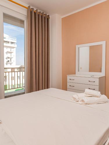 a bedroom with a white bed and a large window at Queen Residence in Shëngjin