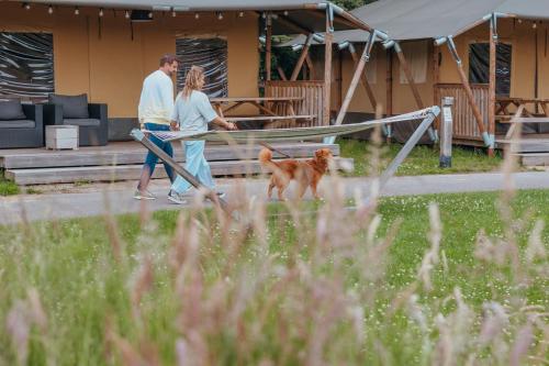 a man and woman walking a dog on a swing at Vakantiepark Sallandshoeve in Nieuw-Heeten