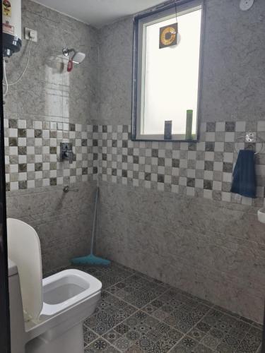 a bathroom with a toilet and a window at Gurgaon 21 Tonic & Twinkle in Gurgaon