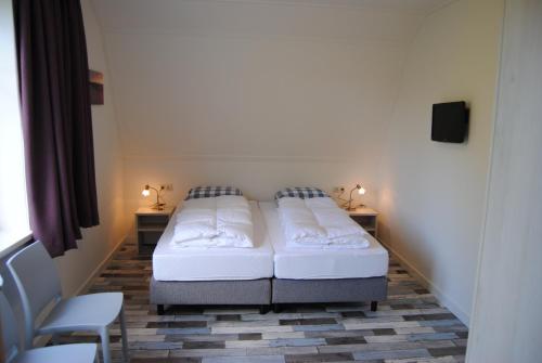 un dormitorio con dos camas y dos sillas en Dunopark Villa, en Oostkapelle