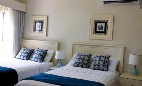 a bedroom with two beds with blue and white pillows at Relax at Private beach, Pools, Acuatic Park & more in Bayahibe