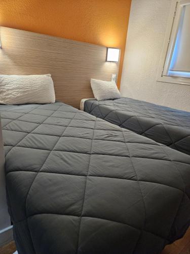 two beds in a hotel room with a large blanket at Premiere Classe Arras - Tilloy Les Mofflaine in Tilloy-lès-Mofflaines