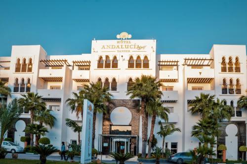 a large white building with palm trees in front of it at Hotel Andalucia Tangier in Tangier