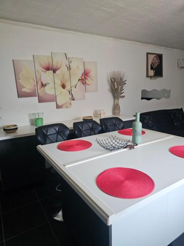 une table blanche avec des plaques rouges au-dessus dans l'établissement Chezoulalandaise, à Mimizan