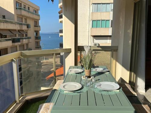 une table verte avec des assiettes et des verres sur un balcon dans l'établissement Appartement Vue Mer 75 m2, à Saint-Raphaël