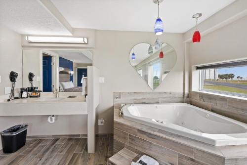 a bathroom with a tub and a sink and a mirror at Blue Wave Inn in Rockport