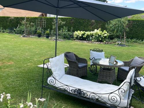 a table and chairs under an umbrella in a yard at Les Prémices De La Forêt in Chailly-en-Bière
