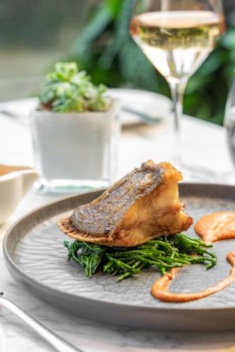 a plate with a piece of meat and a glass of wine at Royal Garden Hotel in London