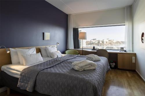 a hotel room with a bed with a towel on it at Scandic Alvik in Stockholm