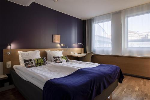 a bedroom with a large bed with blue sheets and pillows at Scandic Alvik in Stockholm