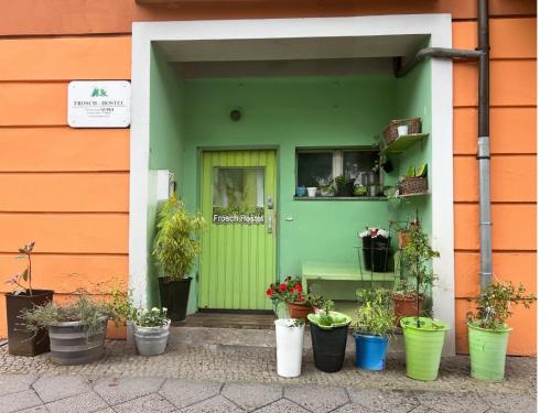 a green door with potted plants in front of a building at Pension Frosch Hostel in Berlin