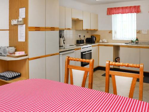una cucina con mobili bianchi, tavolo e sedie di Penlon Cottage a Gwydir