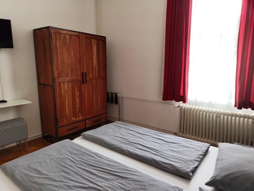 a bedroom with two beds and a wooden cabinet at WHLIVING - Apartments & Studios in Konstanz in Konstanz