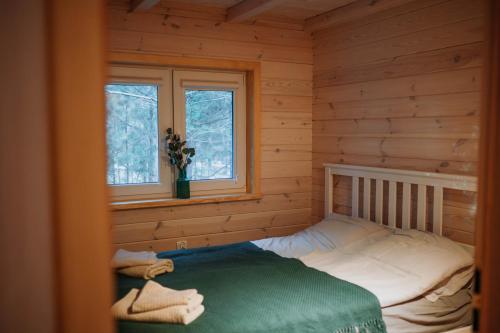 a bedroom with a bed in a log cabin at Zakątek Wygonin Jacuzzi & Sauna w Lesie - KASZUBY in Wygonin