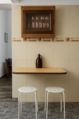 a kitchen with two stools and a counter with a vase at Verde Sol by Célara Aurum - 2BHK Villa with Pool, BBQ & Ice Bath in Panaji
