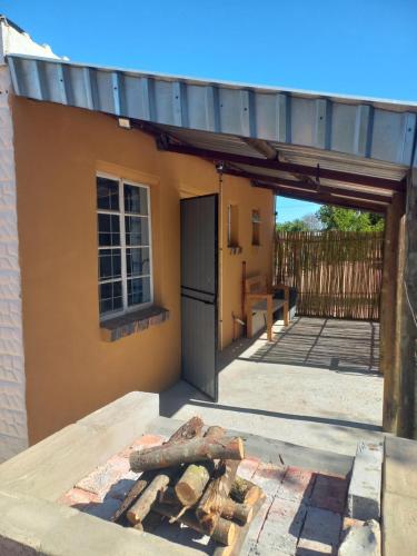 a building with an open door and a pile of wood at Gehuggie in Graafwater