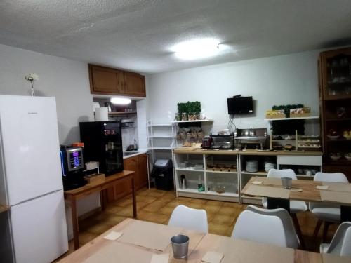 a kitchen with a white refrigerator and tables and chairs at Puente Azud in Avilés