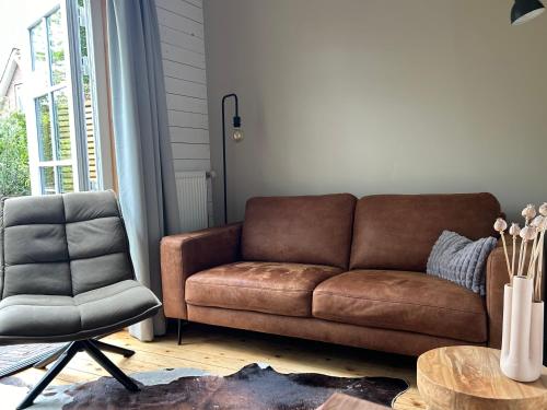 a living room with a brown couch and a chair at Studio Veerse Meer in Wolphaartsdijk