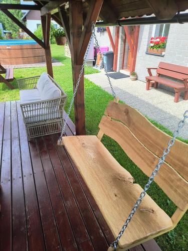 a porch swing with a chair and a bench at Penzion U pily in Paseky nad Jizerou
