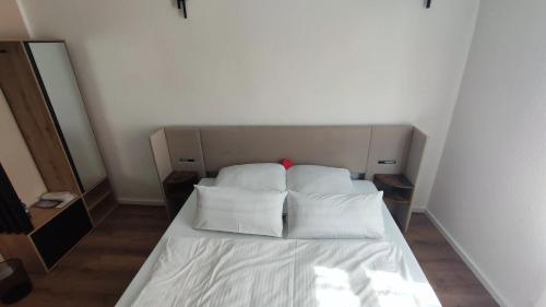 un lit avec des draps blancs et des oreillers dans une chambre dans l'établissement Gasthof Schwarzer Adler, à Limburg an der Lahn