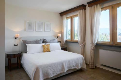 a bedroom with a white bed with two windows at Four Points Flex by Sheraton Naples Marigliano in Marigliano